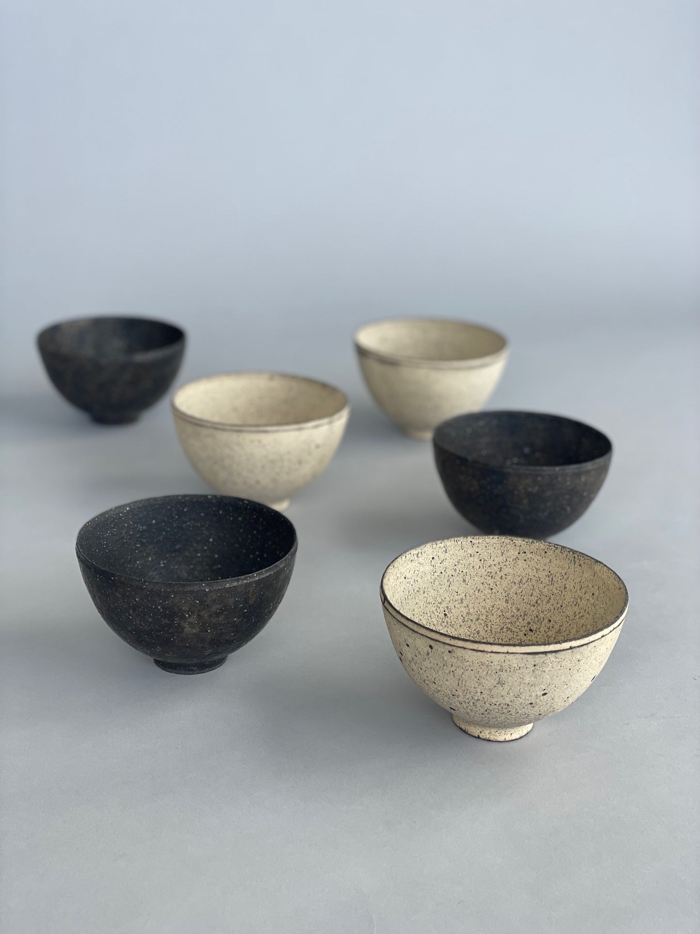 Six handmade ceramic rice bowls. Made by Takashi Endo in a textural white glaze and black glaze.