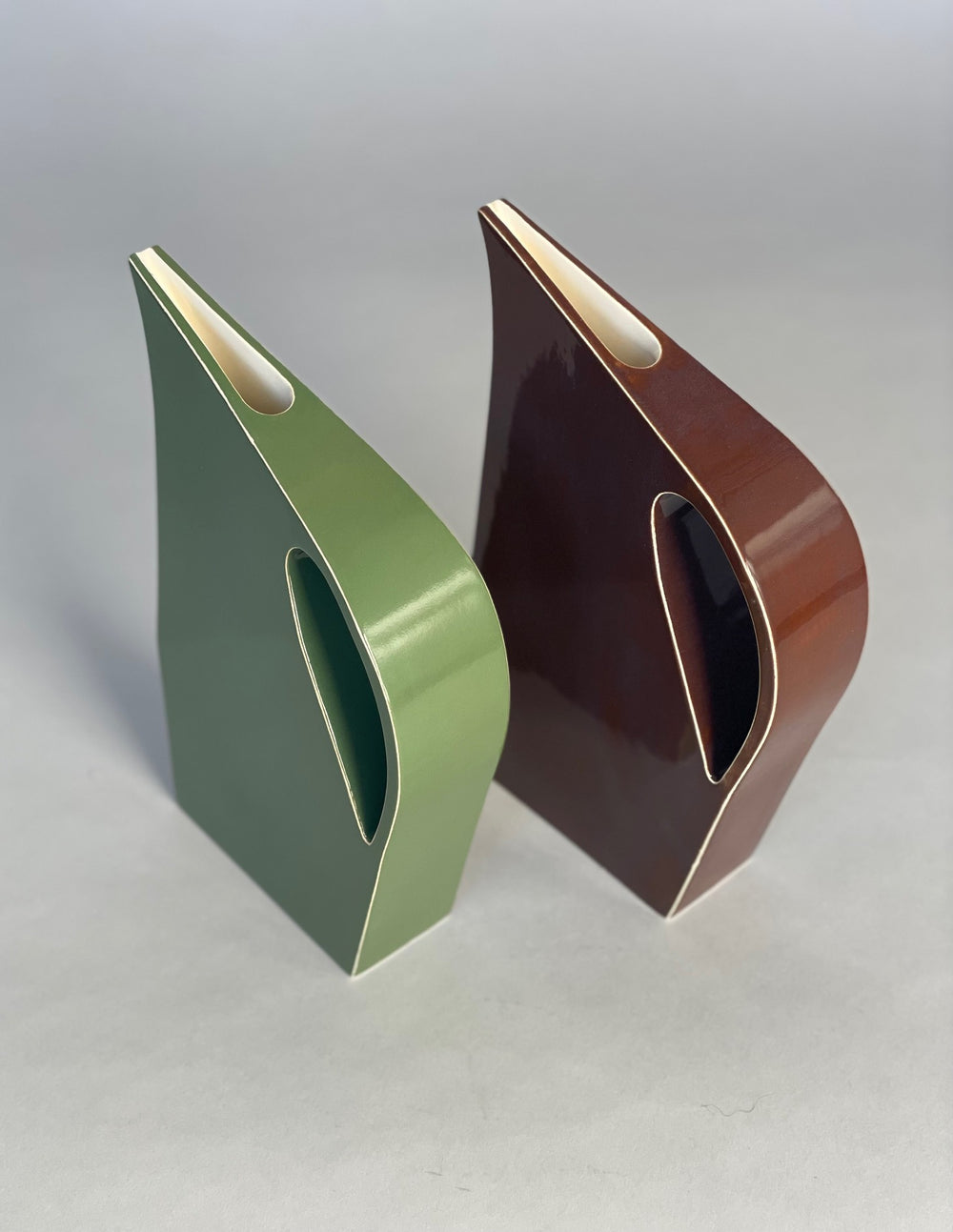 Two Yuro Cuchor handmade jugs in rich  glaze placed side by side on a neutral surface, highlighting their contemporary geometric forms and subtle glaze variations.