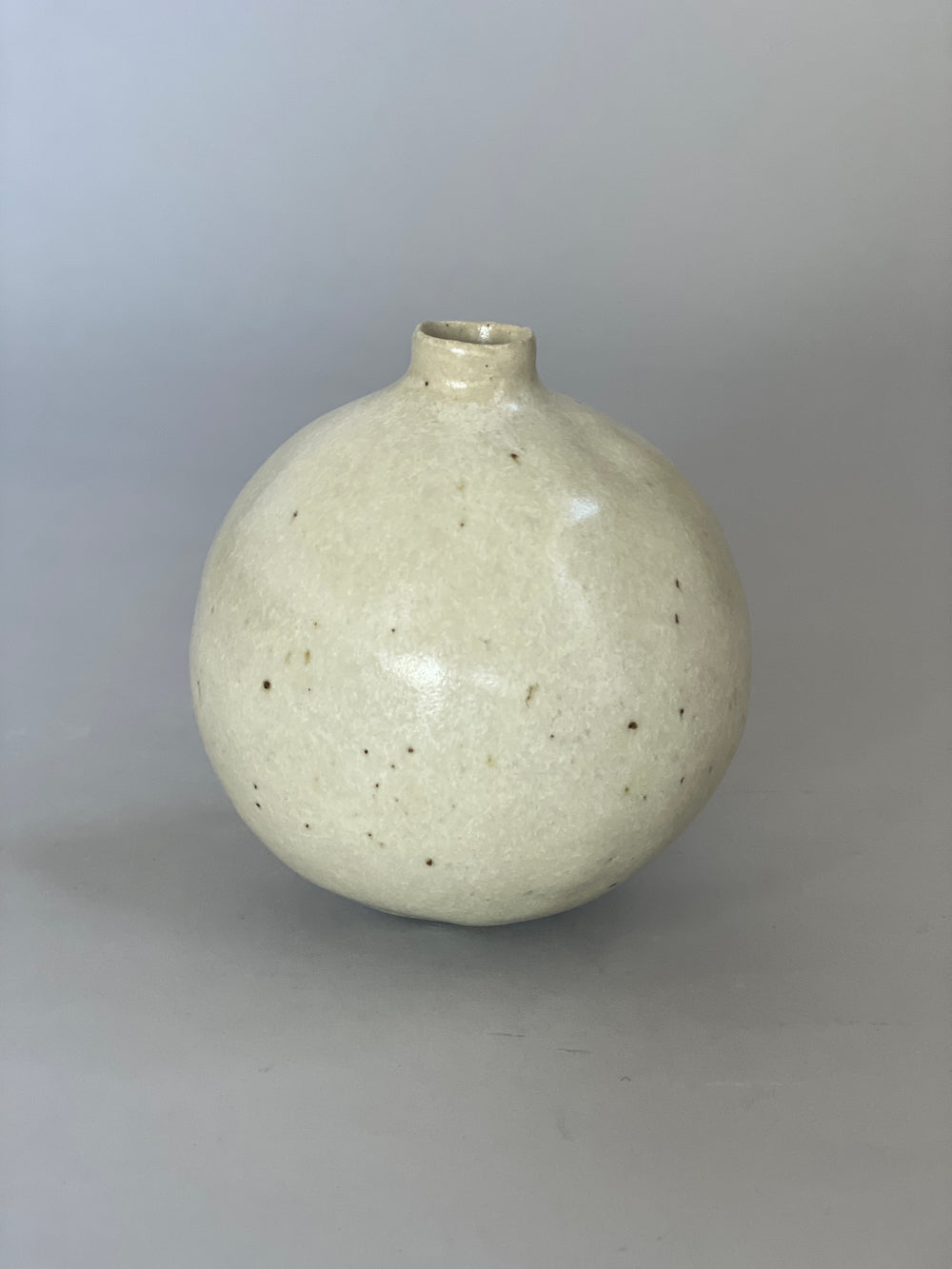 Stoneware vase resting on a minimalist surface, showing the interplay of its warm glaze and light clay.