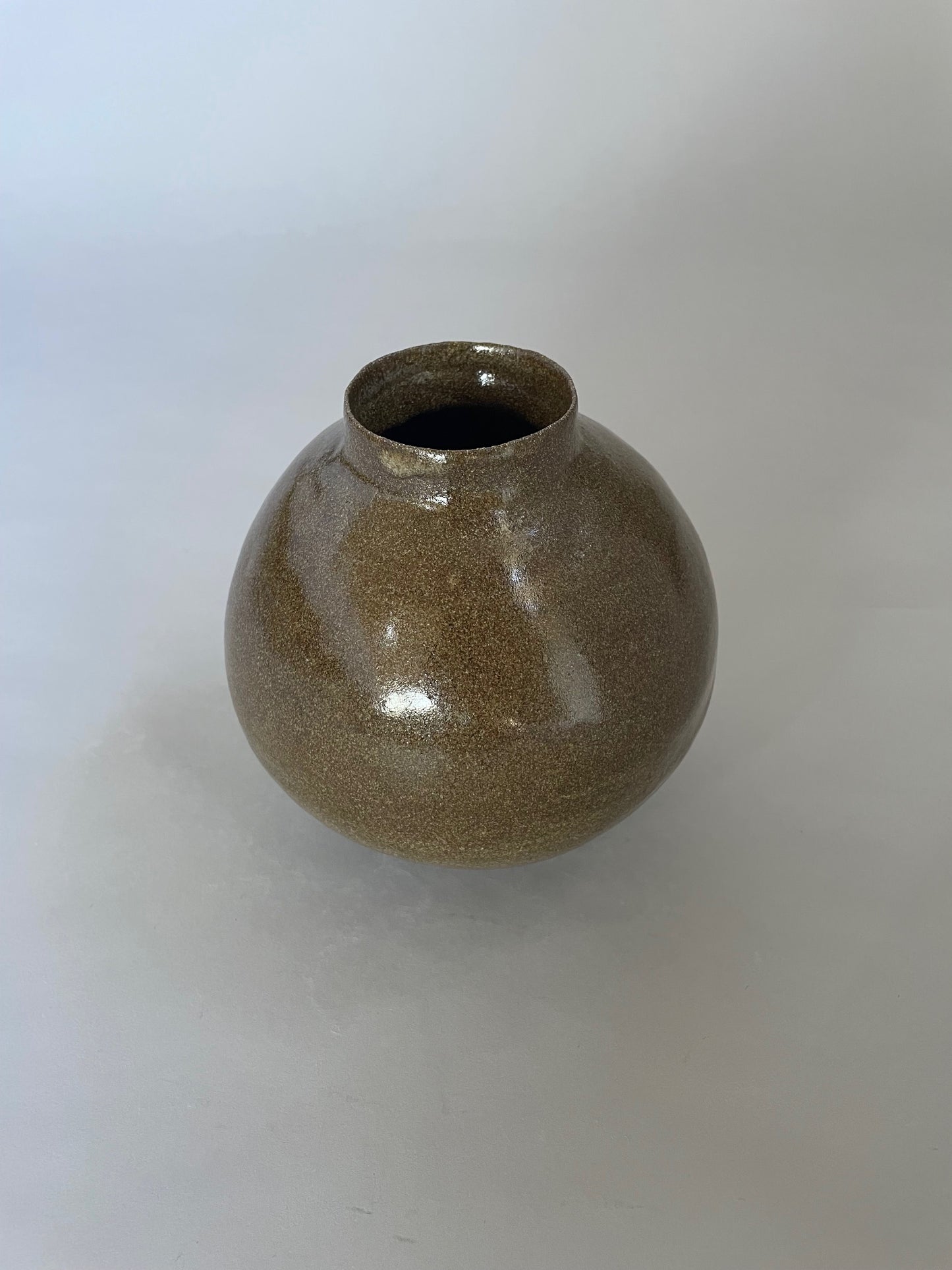 Handmade ceramic vase with a warm earthy glaze and dark clay base, showcasing its unique texture.