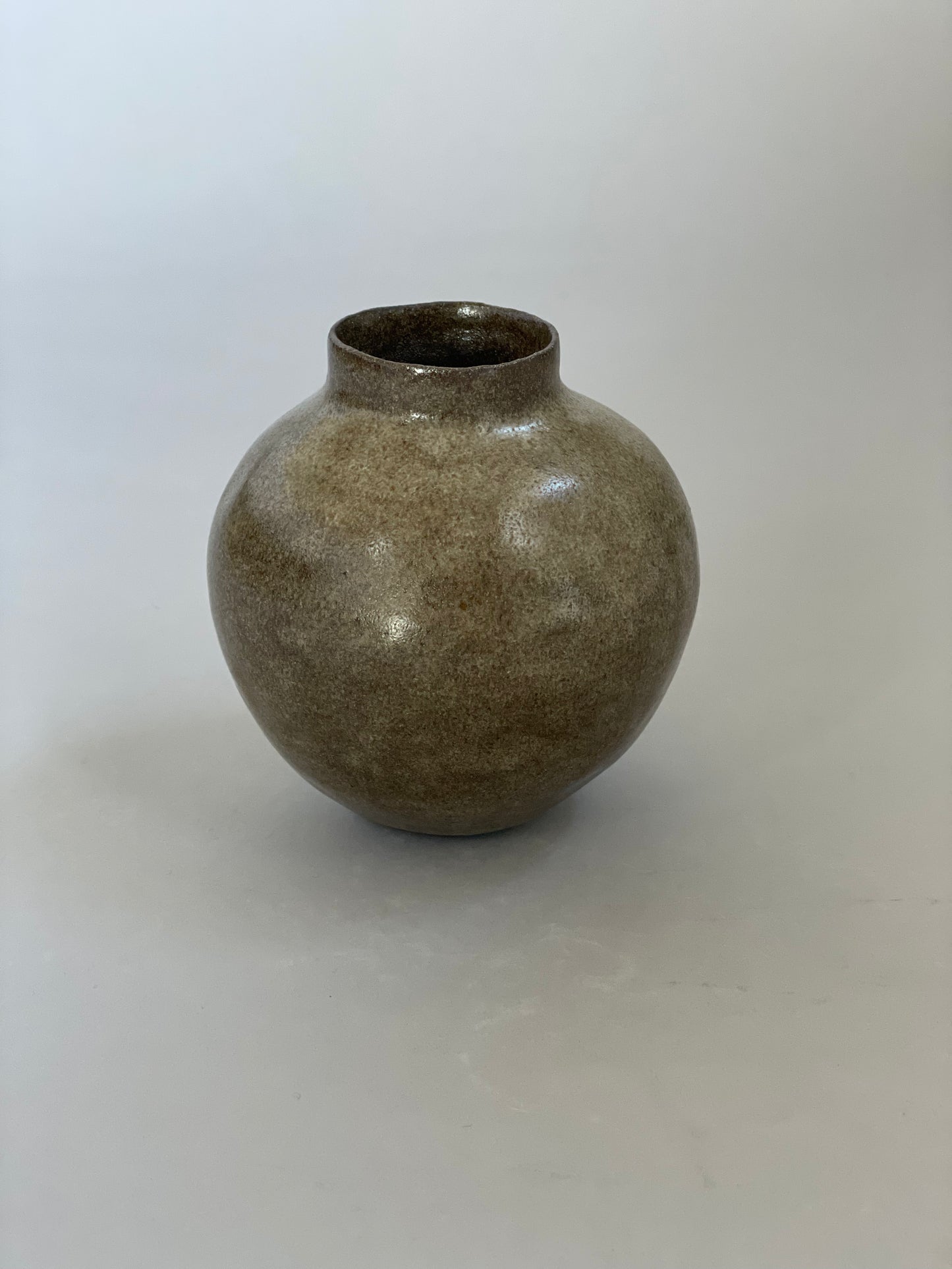 Handmade ceramic vase with a warm earthy glaze and dark clay base, showcasing its unique texture.