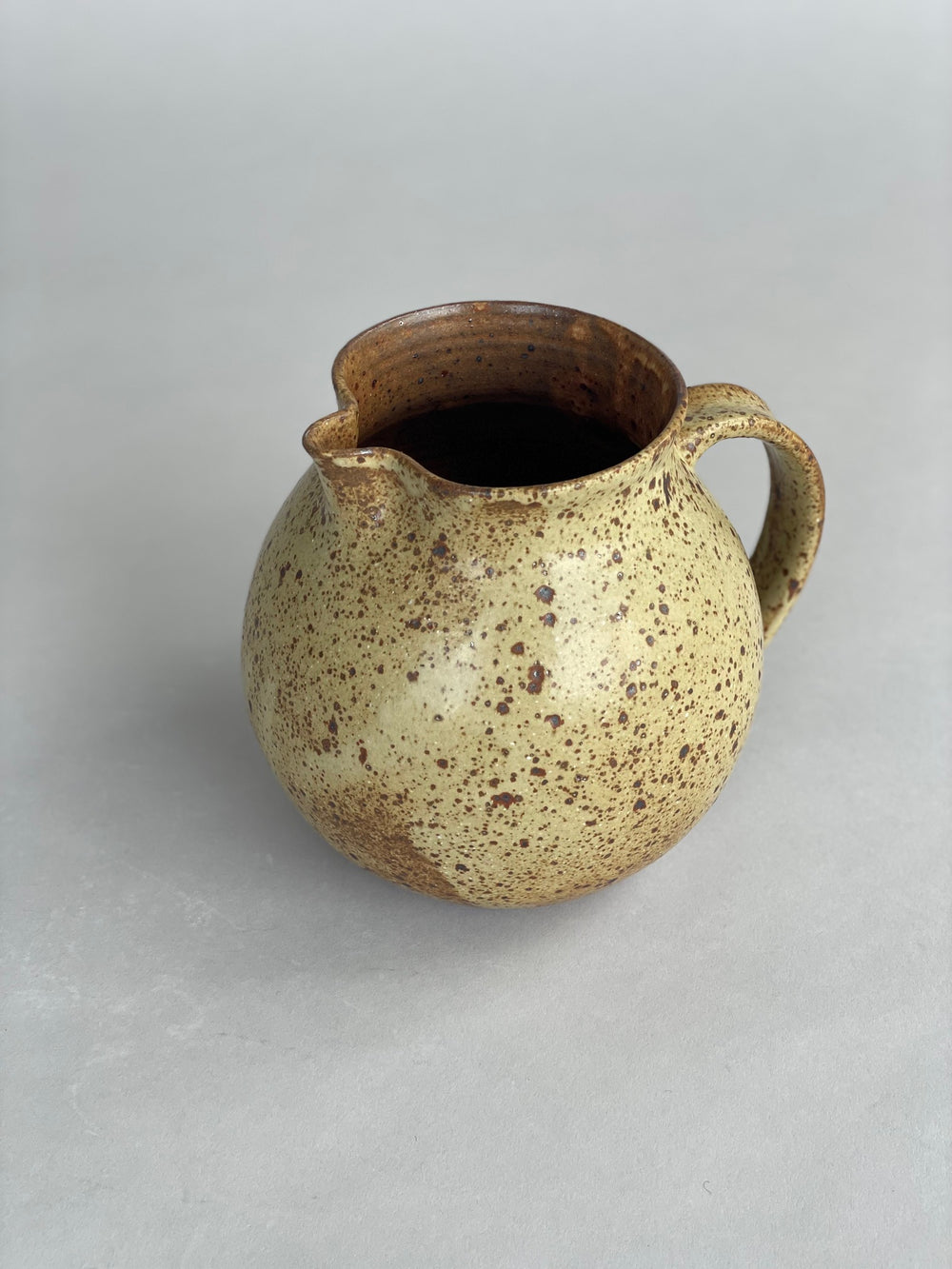 Side view of a speckled stoneware jug, perfect for serving water at the table or in the kitchen.