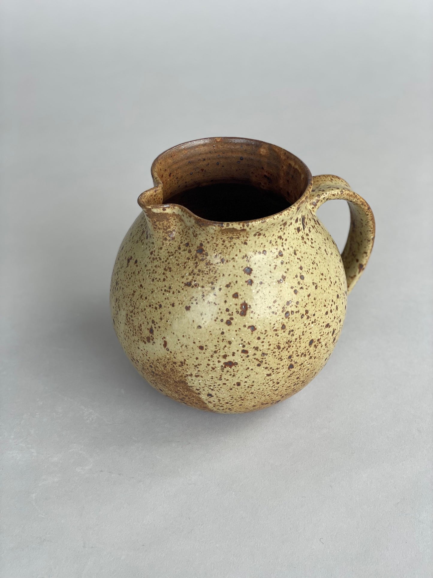 Side view of a speckled stoneware jug, perfect for serving water at the table or in the kitchen.