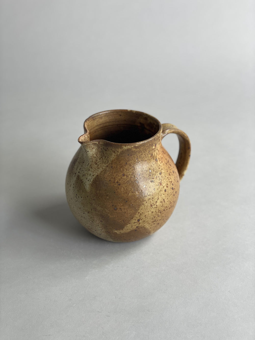 Handmade ceramic water jug with a warm speckled glaze, blending classic and modern design.
