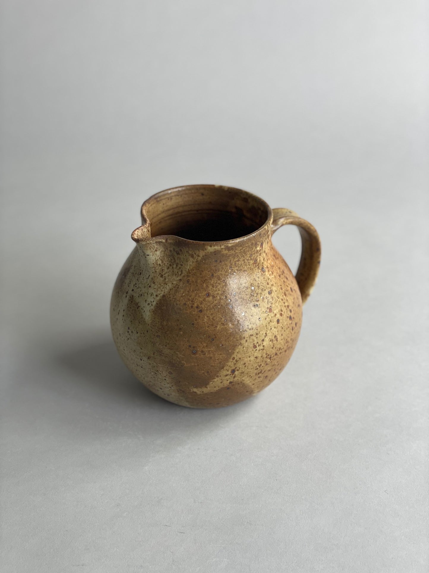 Handmade ceramic water jug with a warm speckled glaze, blending classic and modern design.