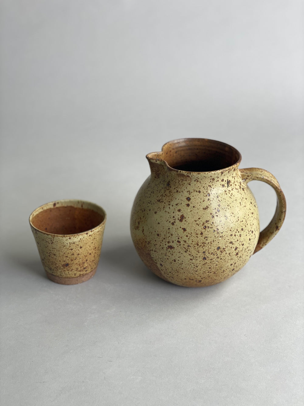 Handmade ceramic water jug paired with a matching speckled tumbler, creating a cohesive and modern tabletop set.