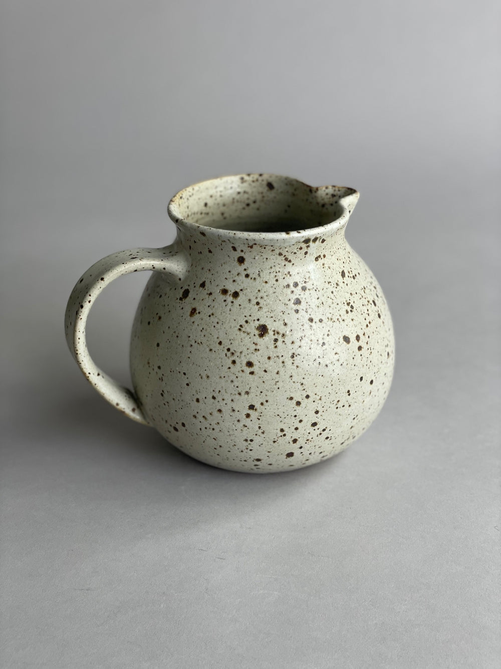 Handmade ceramic water jug with a warm speckled glaze, blending classic and modern design.