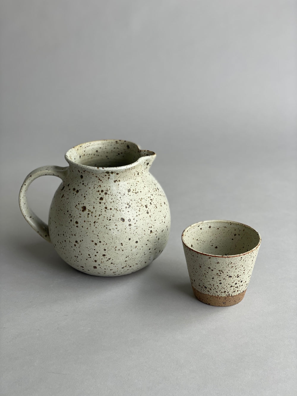 A water jug resting on a wooden counter, highlighting its simple form and warm speckled finish.