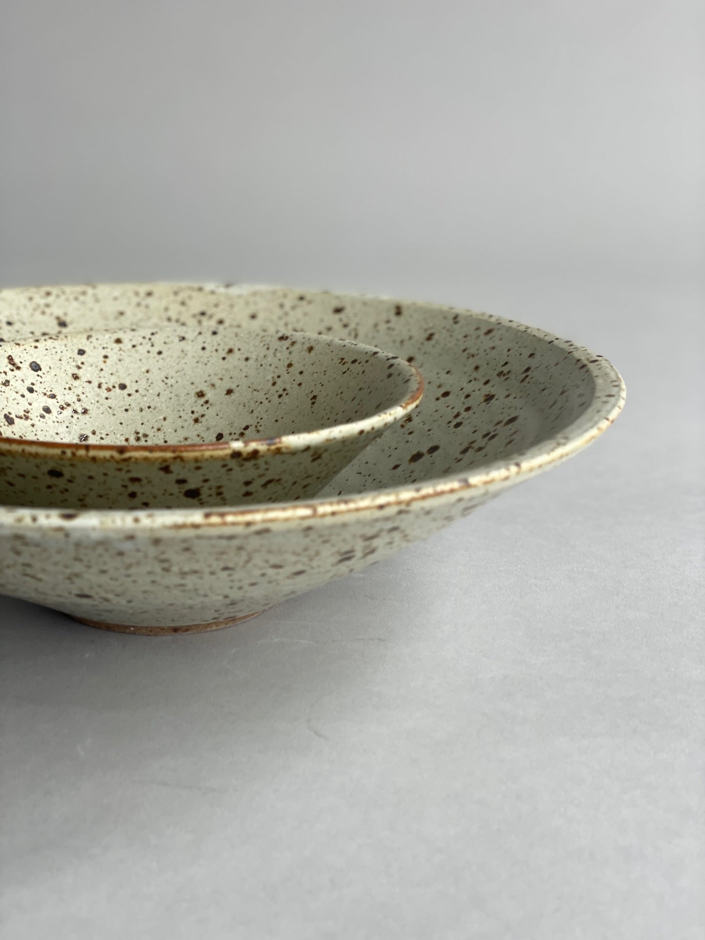 Close-up of a stoneware bowl by Larisa Milsum, highlighting its textured finish and unique glaze.