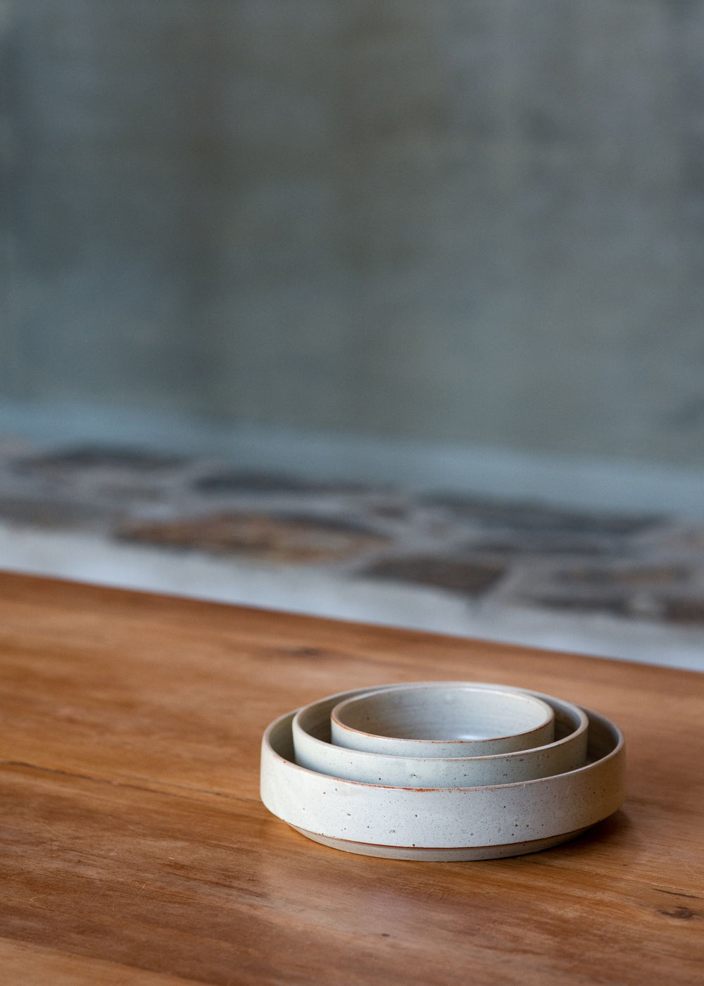 Set of three nesting ceramic bowls in soft white glaze, elegantly stacked to showcase their timeless design.