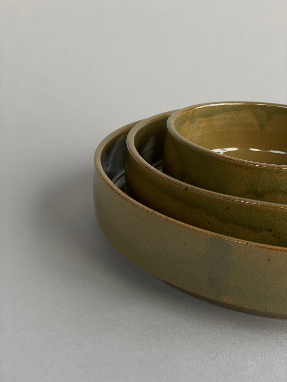 Side view of stacked green ceramic bowls, highlighting their elegant proportions and artisanal craftsmanship.