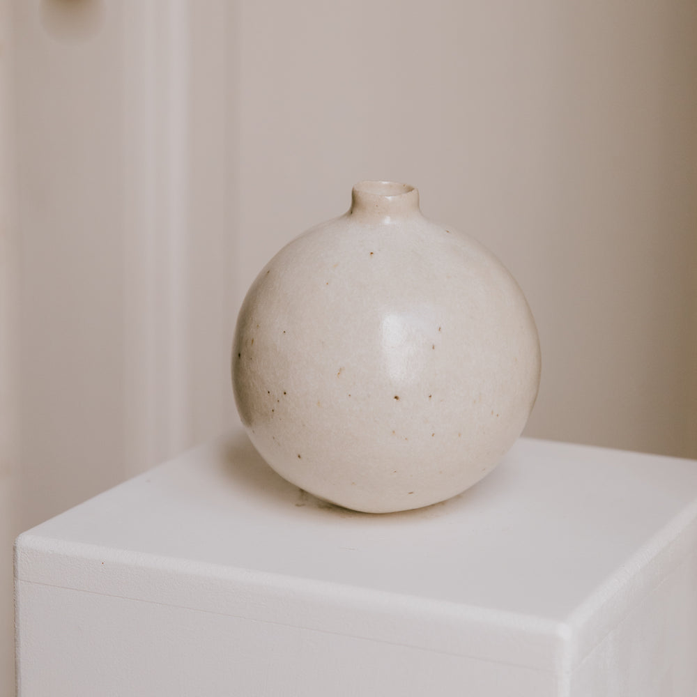Stoneware vase resting on a minimalist surface, showing the interplay of its warm glaze and light clay.