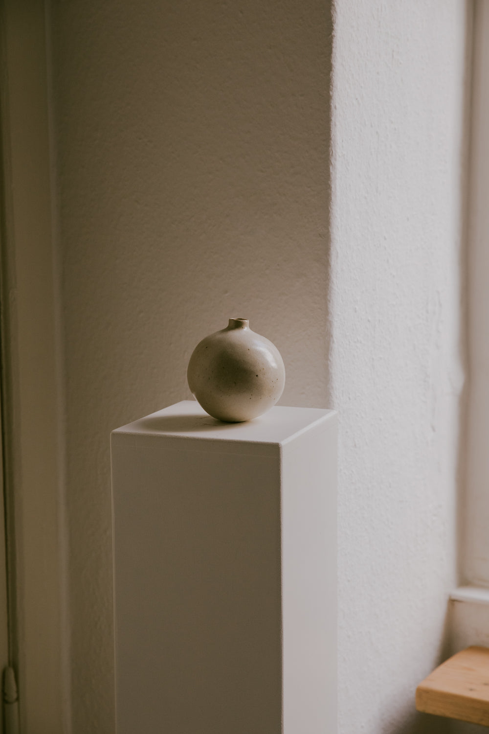 Stoneware vase resting on a minimalist surface, showing the interplay of its warm glaze and light clay.