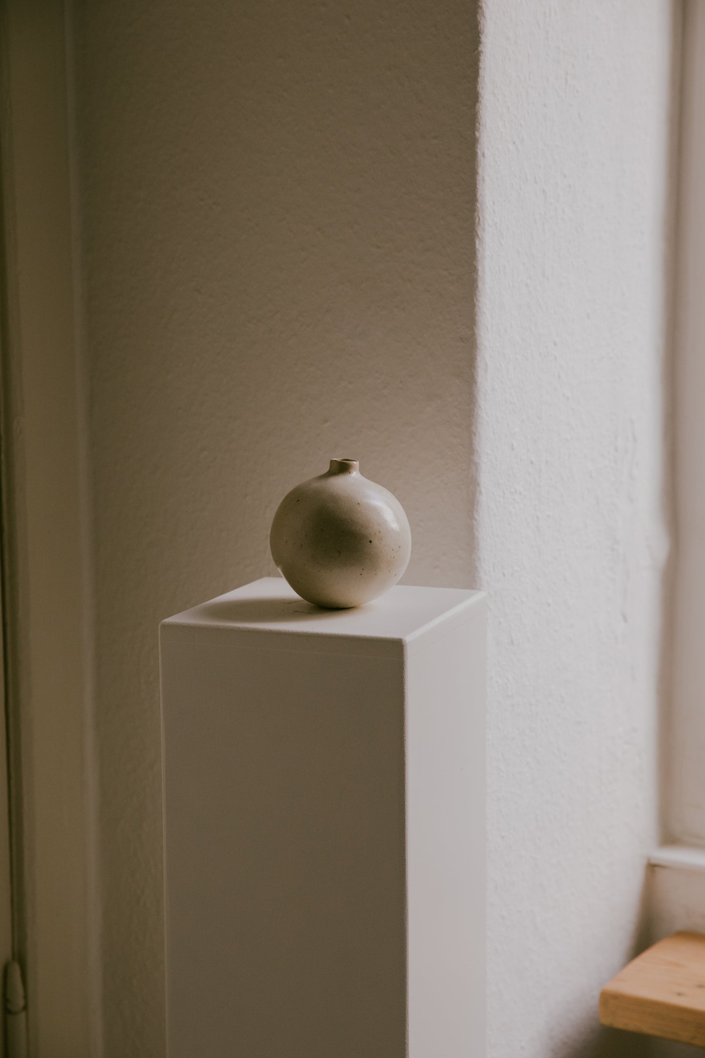 Stoneware vase resting on a minimalist surface, showing the interplay of its warm glaze and light clay.