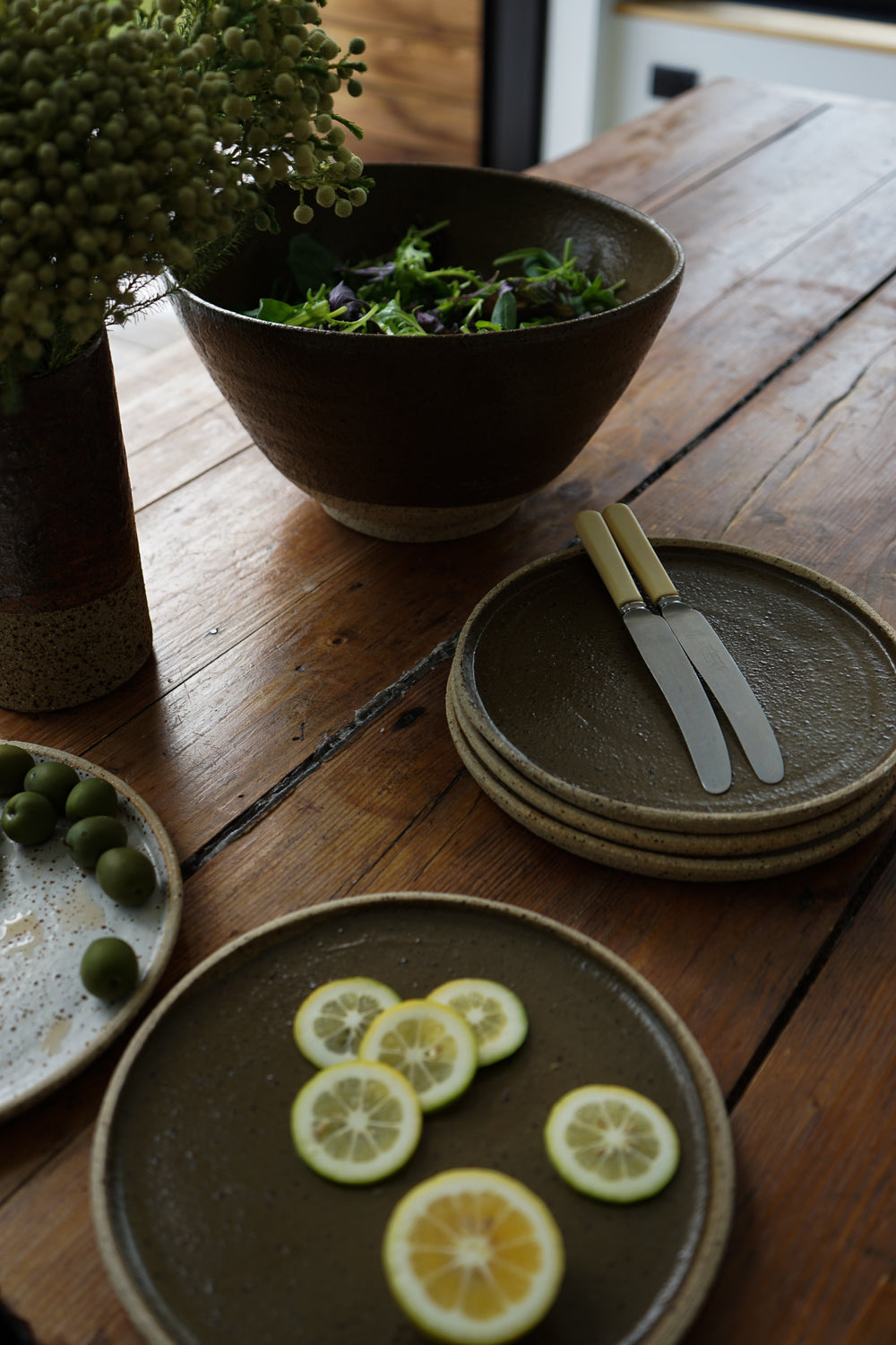 Special deep earthy green handmade plates made exclusively for Situ Studio by Auckland potter Kirsten Dryburgh.  Photographed on a dining table