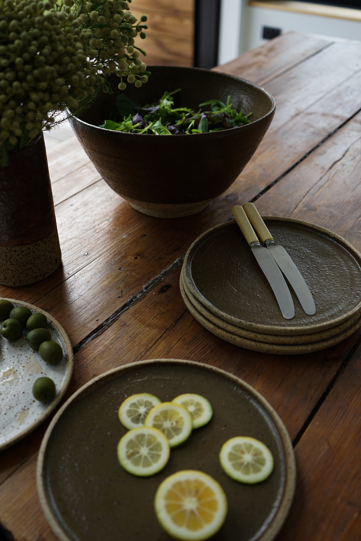 Special deep earthy green handmade plates made exclusively for Situ Studio by Auckland potter Kirsten Dryburgh.  Photographed on a dining table