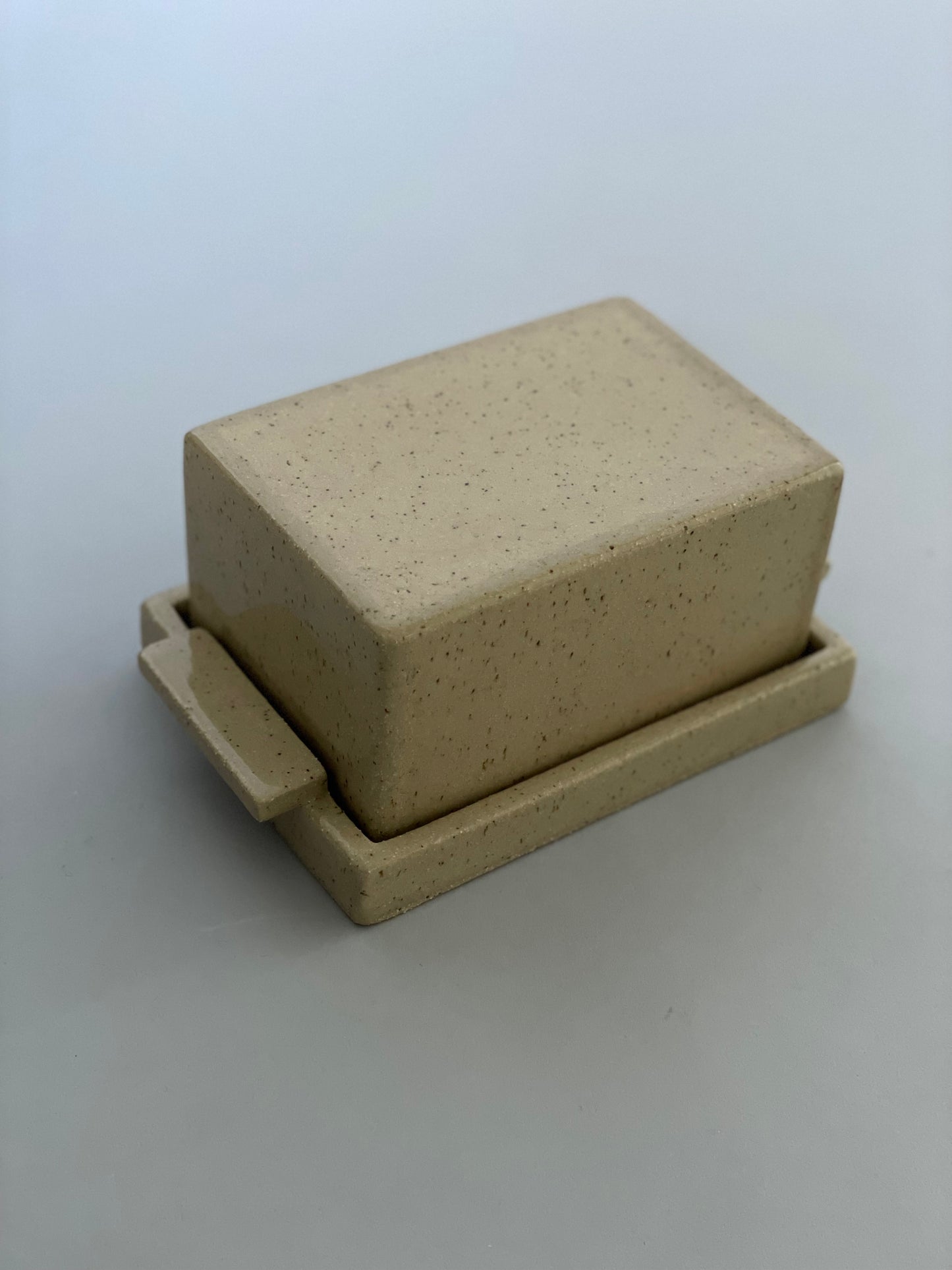 Handmade ceramic butter dish with a lid by Misma Anaru. A lovely speckled natural sand toned clay has been used with the form having straight lines.