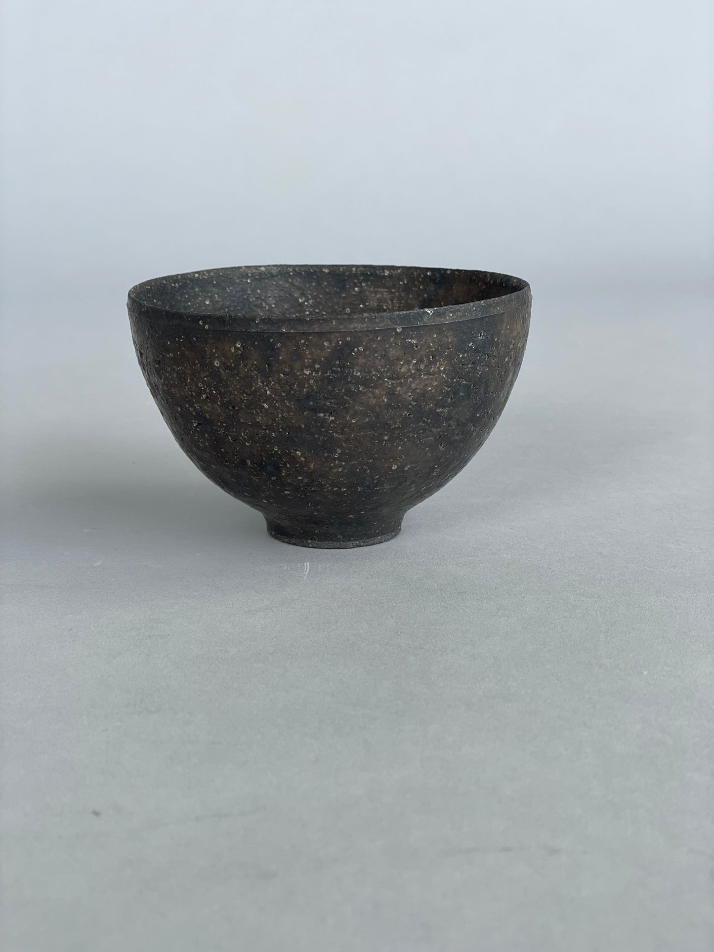 A single handmade ceramic rice bowl. Made by Takashi Endo in a textural  black glaze.