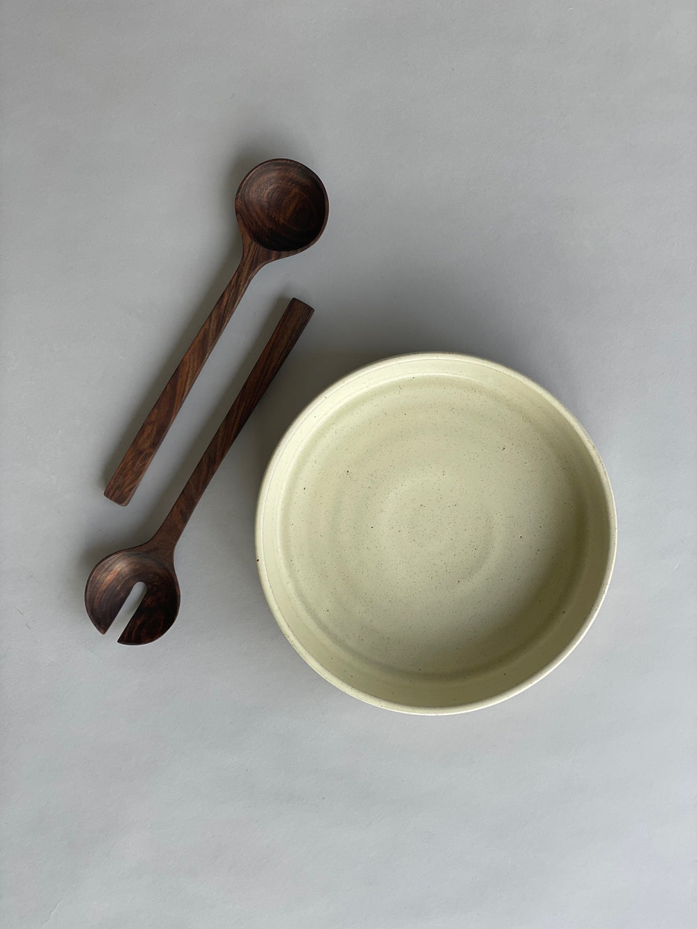 Serving set arranged on a dining table, highlighting the contrast between the warm white bowl and rich walnut servers.