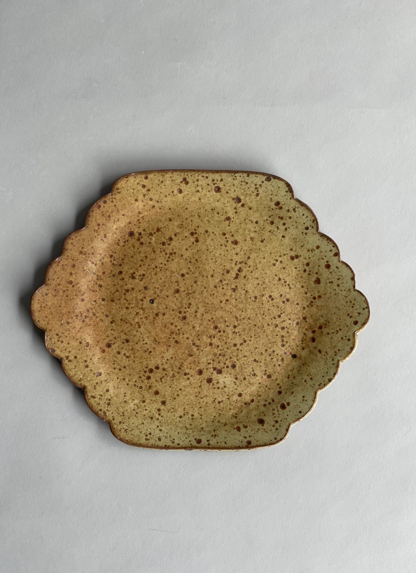 Handmade ceramic plate with a warm speckled glaze, showcasing a simple yet distinctive design.