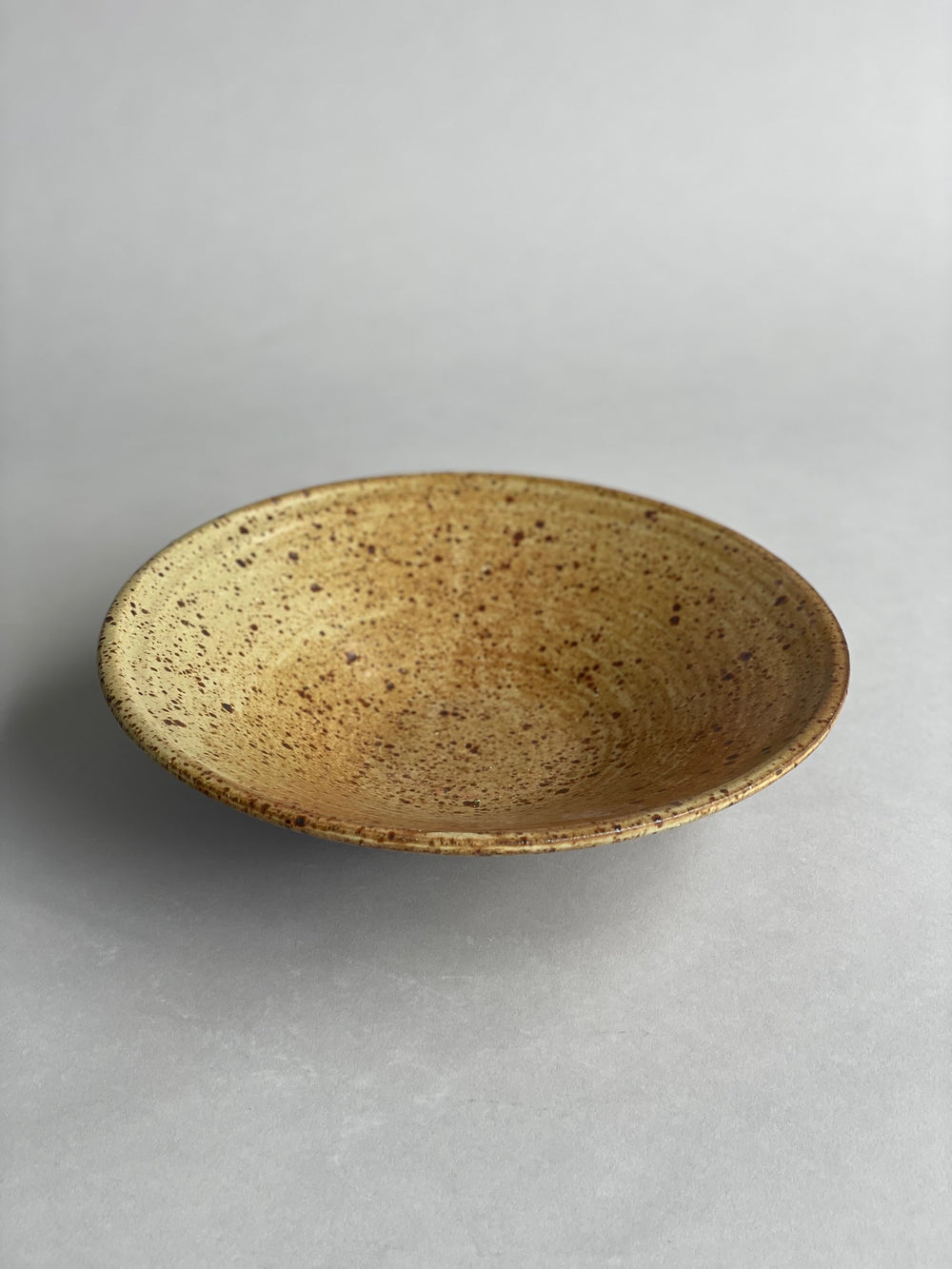 Top-down view of a stoneware bowl, highlighting its smooth interior and organic craftsmanship.