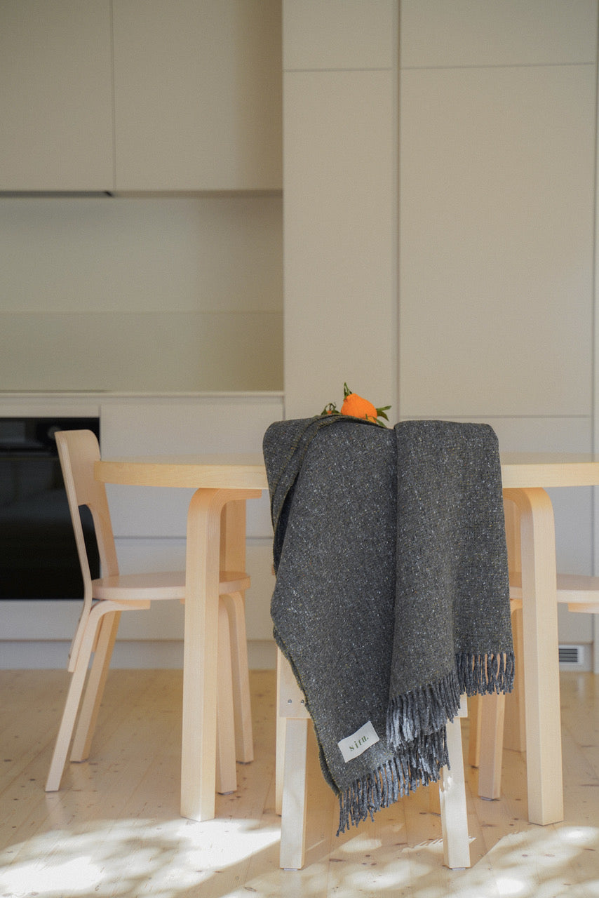 Heirloom Edition blanket on a cozy dining chair, adding warmth and texture to the space.