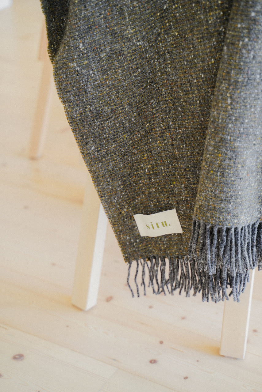 Close-up of a Heirloom Edition wool blanket, showcasing the tweed weave in Slate and Moorland Green tones.