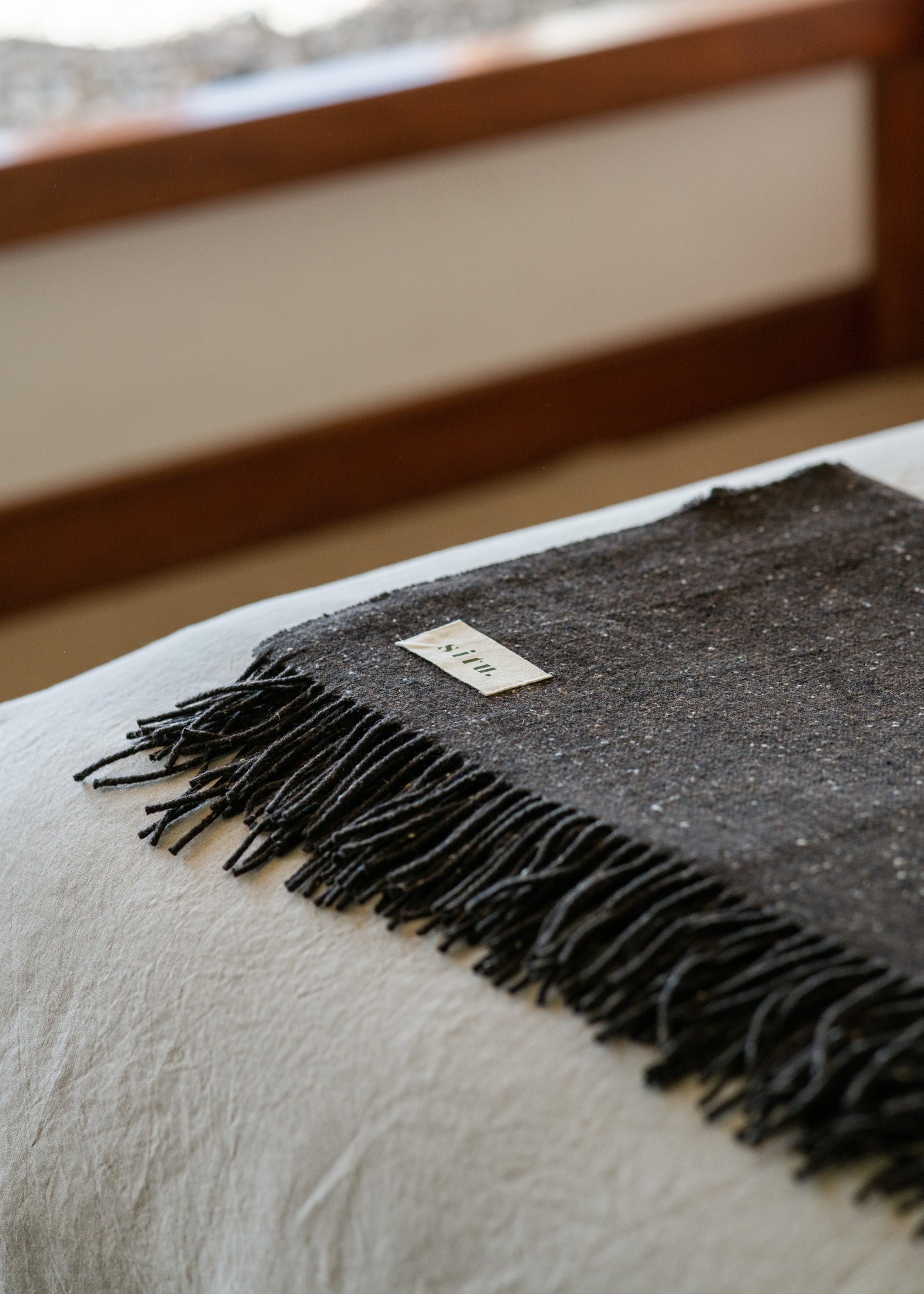 Handwoven wool blanket folded on a bed, perfect for adding warmth and texture to any space.