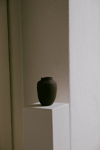 Handmade stoneware vase with a raw dark clay exterior and earthy glazed interior.