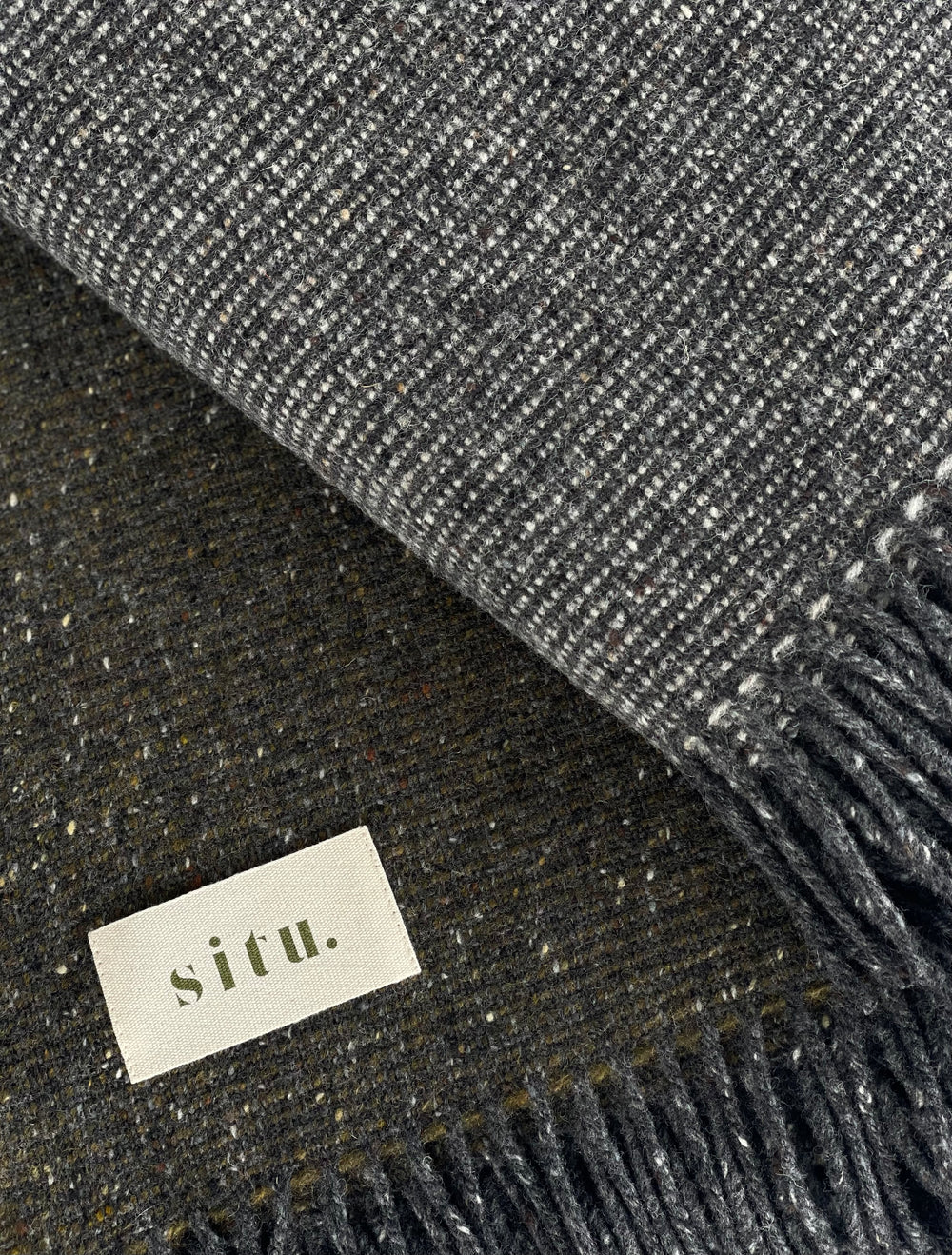 Close-up of a Heirloom Edition wool blanket, showcasing the tweed weave in Slate and Moorland Green tones.