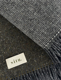 Close-up of a Heirloom Edition wool blanket, showcasing the tweed weave in Slate and Moorland Green tones.