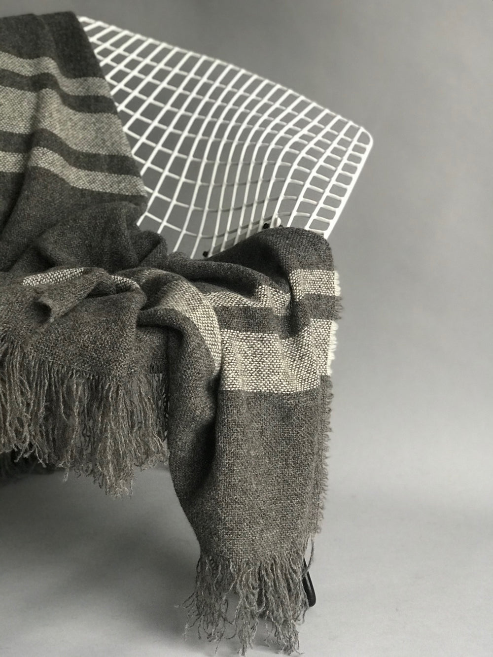 Soft luxurious wool throw made in New Zealand and designed by Situ Studio. A natural dark grey with an ecru stripe making this blanket a classic to style your home with. Made to last and to use everyday.