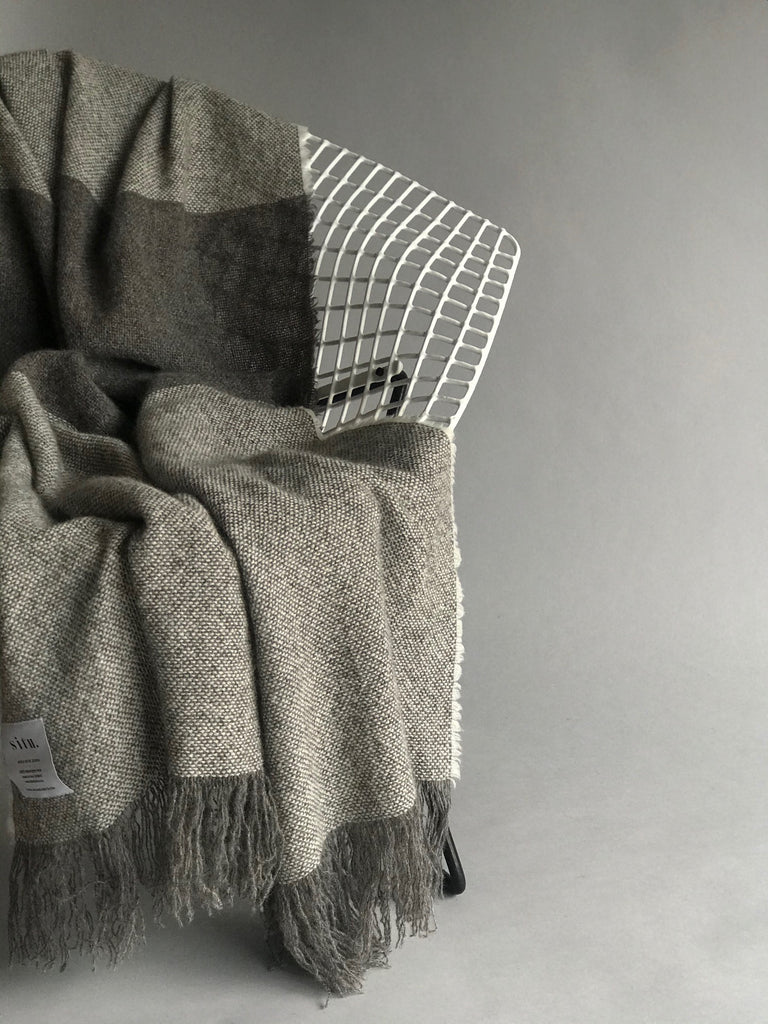 Soft luxurious wool throw made in New Zealand and designed by Situ Studio. A natural dark grey with an ecru stripe making this blanket a classic to style your home with. Made to last and to use everyday.