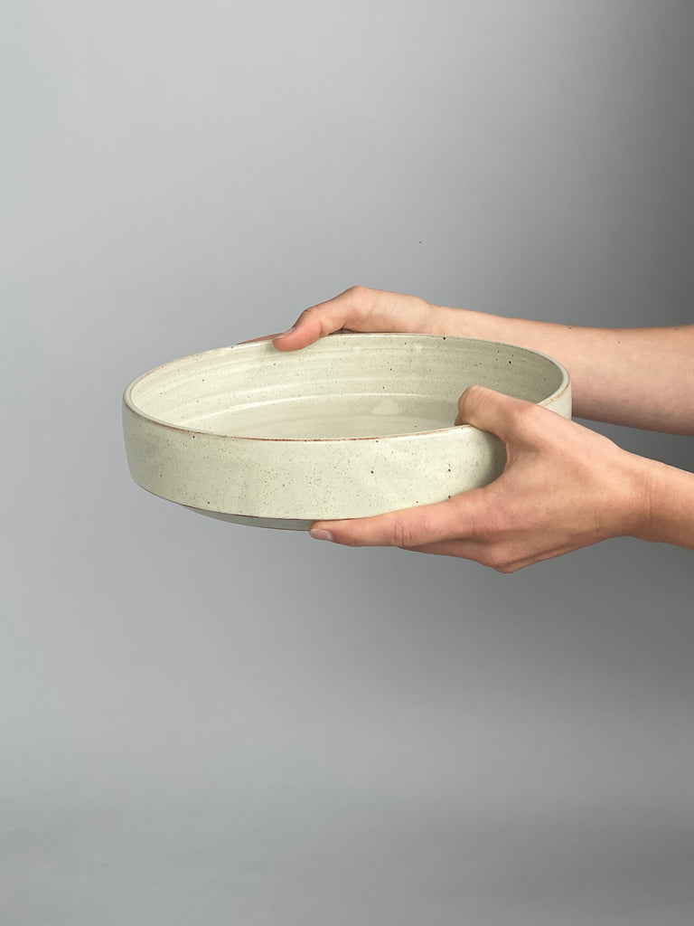 A warm white handmade ceramic serving bowl, which is stackable and modern in shape. Made by Christchurch potter Richard Beauchamp.