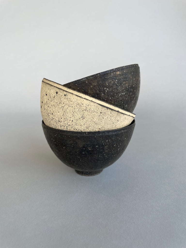 A stack of beautiful bowls by ceramic artist, Takashi Endo. Both the black and white bowls have a textural aesthetic 