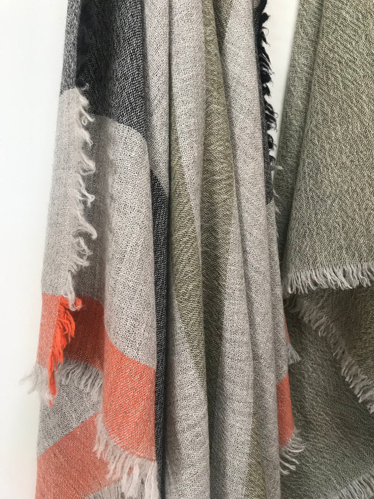 Lightweight and soft wool blanket made in New Zealand and designed by Situ Studio. A light grey wool with intermittent stripes of Olive Green, Charcoal and orange.