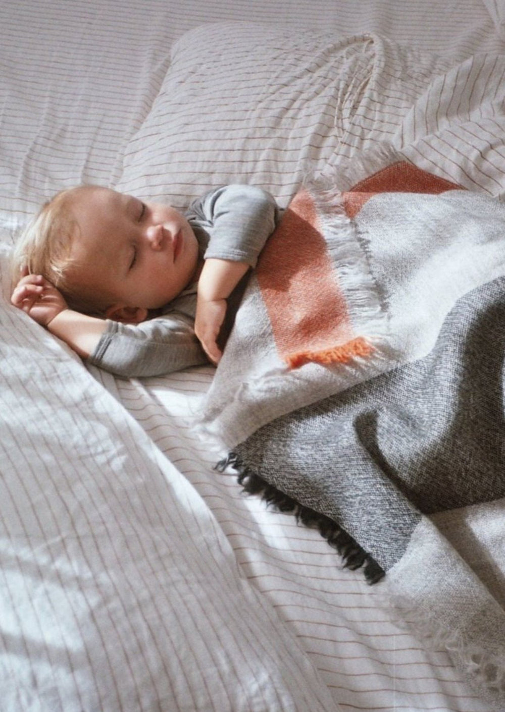 Lightweight and soft wool blanket made in New Zealand and designed by Situ Studio. A light grey wool with intermittent stripes of Olive Green, Charcoal and orange.