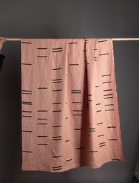 A folded linen throw with geometric patterns, highlighting its natural fibers and sustainable craftsmanship.