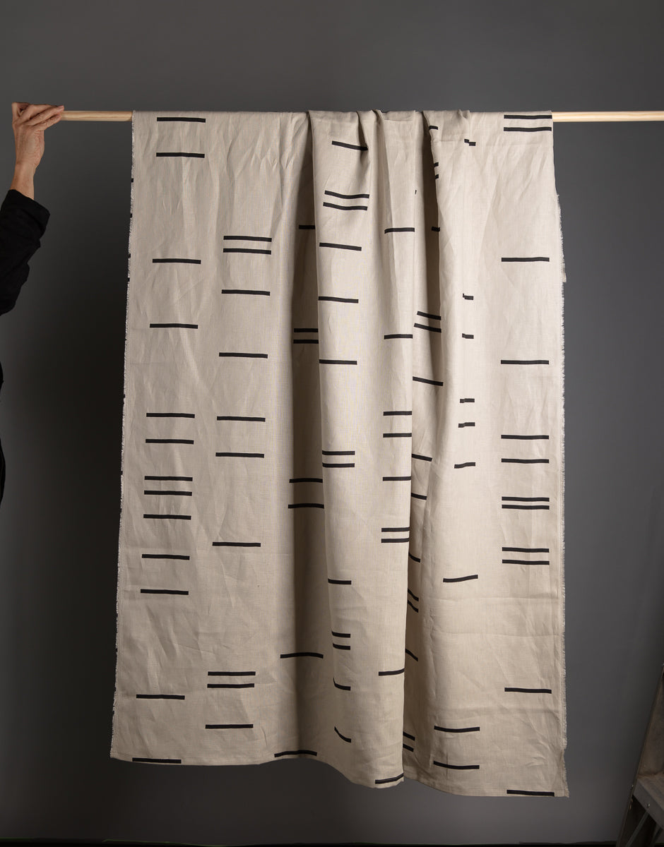 Screen-printed linen blanket draped over a stick.