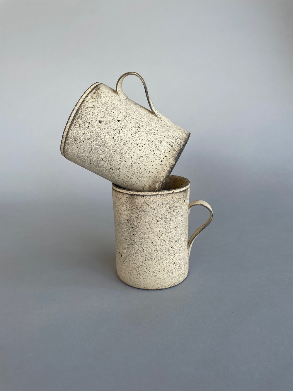 Group of monochromatic ceramic cups arranged together, emphasizing their textured stone-like surfaces.